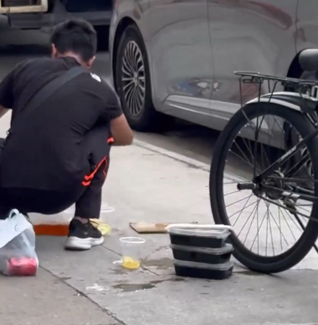 一名外賣員倒瀉了兩杯凍檸茶在外賣袋內,遂在路邊蹲地「急救」,將袋內茶水倒回杯內,試圖變回原狀。(Threads)