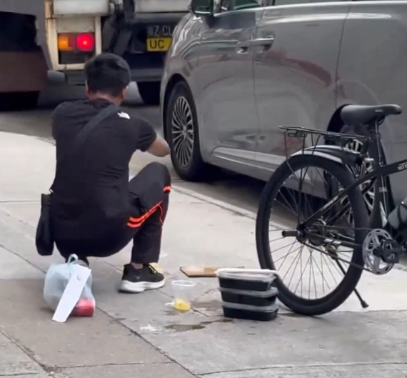一名外賣員倒瀉了兩杯凍檸茶在外賣袋內,遂在路邊蹲地「急救」,將袋內茶水倒回杯內,試圖變回原狀。(Threads)