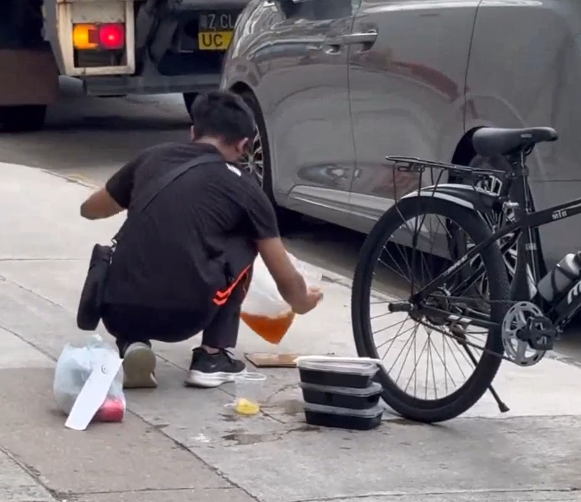 一名外賣員倒瀉了兩杯凍檸茶在外賣袋內,遂在路邊蹲地「急救」,將袋內茶水倒回杯內,試圖變回原狀。(Threads)