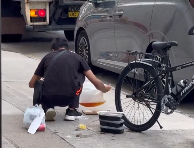 一名外賣員倒瀉了兩杯凍檸茶在外賣袋內,遂在路邊蹲地「急救」,將袋內茶水倒回杯內,試圖變回原狀。(Threads)