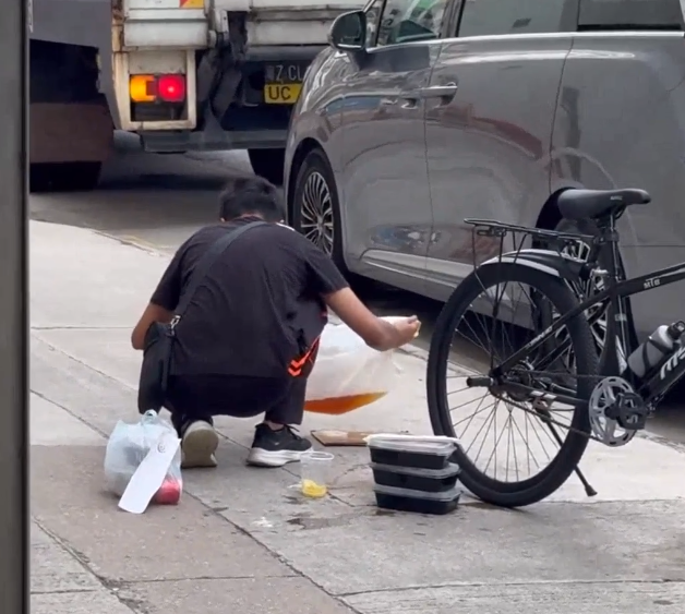 一名外賣員倒瀉了兩杯凍檸茶在外賣袋內,遂在路邊蹲地「急救」,將袋內茶水倒回杯內,試圖變回原狀。(Threads)