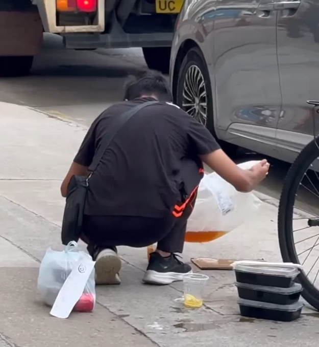 一名外賣員倒瀉了兩杯凍檸茶在外賣袋內,遂在路邊蹲地「急救」,將袋內茶水倒回杯內,試圖變回原狀。(Threads)