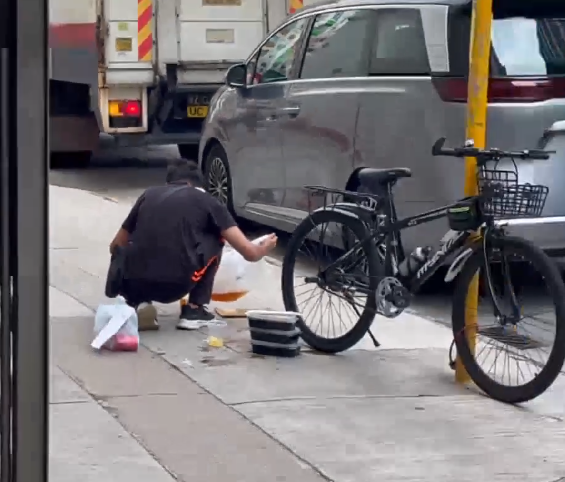一名外賣員倒瀉了兩杯凍檸茶在外賣袋內,遂在路邊蹲地「急救」,將袋內茶水倒回杯內,試圖變回原狀。(Threads)