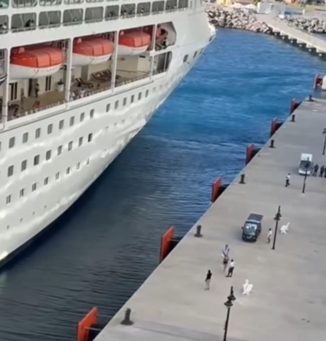 一輛黑色高爾夫球車載著一男一女駛至碼頭,但兩人只能眼白白看著郵輪離去。