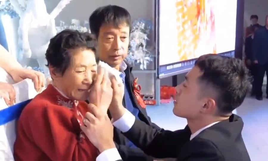 新郎卻微笑不住幫她抺去眼淚十分呵護,還像逗小孩搬在臉上劃個笑面,著母親別哭。(微博)