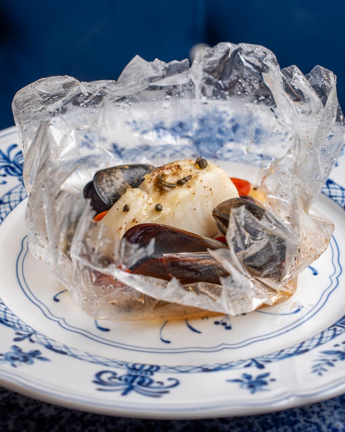 焗白鱈魚配青口及番茄($298)用意大利耐溫玻璃紙密封包裹焗煮,鎖著每一滴精華,海鮮保持鮮嫩多汁。