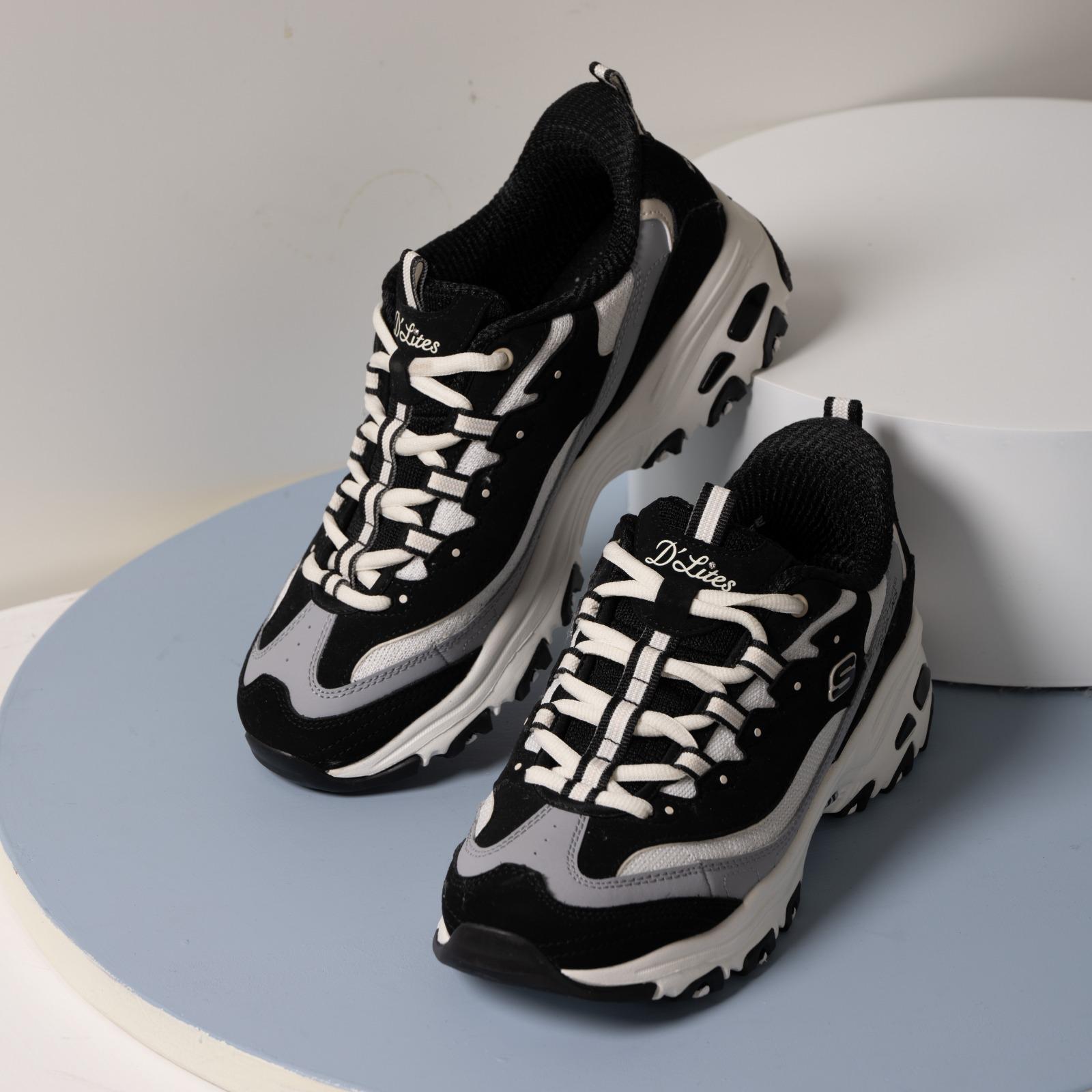 D'Lites首度搭載Hands Free Slip-ins®科技 熊貓主調鞋款同步登場 延續系列靈感,Panda Pack同步推出多款成人及小童D’Lites鞋款,演繹從頭到腳的熊貓系穿搭。是次全新女裝鞋Hands Free Slip-ins®: D'Lites,首度將品牌王牌舒適科技SKECHERS Hands Free Slip-ins®站立穿脫科技注入D’Lites經典輪廓,配合專利Heel Pillow™鞋跟設計,讓用家無需彎腰或動手即可輕鬆穿上鞋履,實現解放雙手、「一秒閃穿,即穿即走」的便捷穿脫體驗。另外,D’Lites亦配有Air-Cooled Memory Foam®透氣記憶棉鞋墊,帶來舒適且穩定的承托效能。鞋面採用多層皮革、網布及針織物料拼接,結合條紋鞋帶細節,設計感與機能兼備。加上1.5吋加高鞋跟,修飾身形比例,為穿搭增添時尚感。