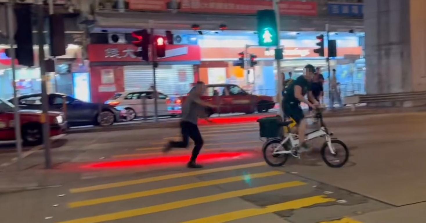 一名的士司機離開其座駕,在馬路上追趕一名騎單車的男子,期間的士司機撲前意圖捉住單車惟失手撲空,整個人如滾地葫蘆向前倒地。(Threads)