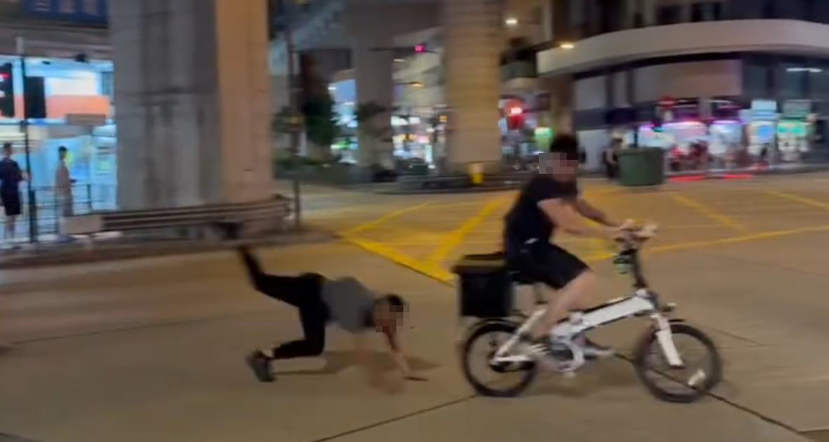一名的士司機離開其座駕,在馬路上追趕一名騎單車的男子,期間的士司機撲前意圖捉住單車惟失手撲空,整個人如滾地葫蘆向前倒地。(Threads)