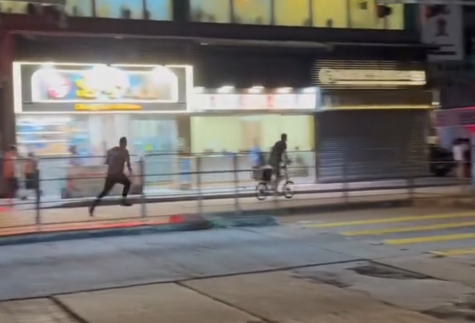 一名的士司機離開其座駕,在馬路上追趕一名騎單車的男子,期間的士司機撲前意圖捉住單車惟失手撲空,整個人如滾地葫蘆向前倒地。(Threads)