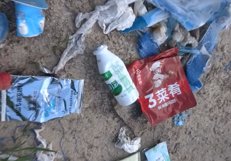 西貢萬宜水庫東壩近日成為遊客旅遊熱點,有網民近日於東壩近破邊洲一處泥地發現大堆垃圾,大部分食物包裝均印有簡體字,立即拍片公審,擔憂污染水源及郊野環境。(fb影片截圖)
