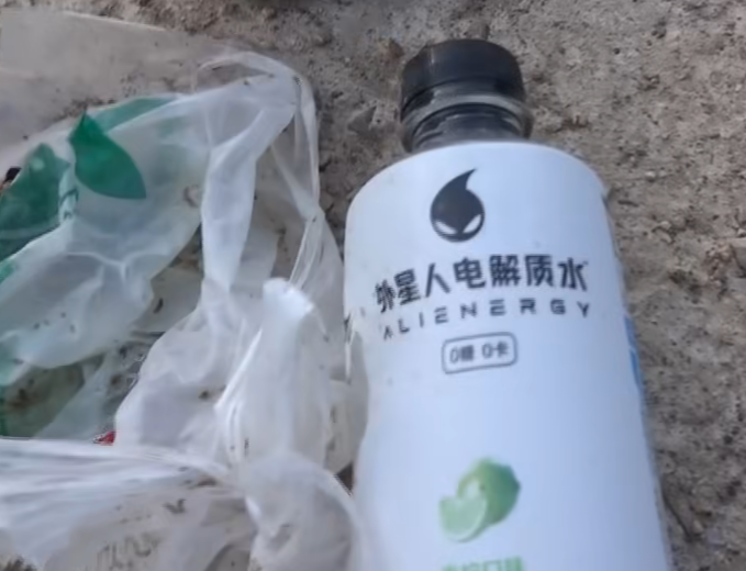 西貢萬宜水庫東壩近日成為遊客旅遊熱點,有網民近日於東壩近破邊洲一處泥地發現大堆垃圾,大部分食物包裝均印有簡體字,立即拍片公審,擔憂污染水源及郊野環境。(fb影片截圖)