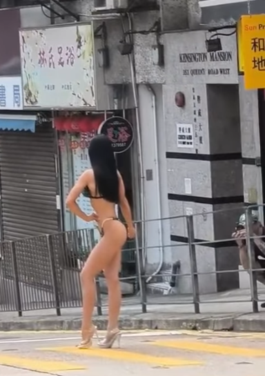 有網民上載影片,現場在西營盤西邊街及皇后大道西交界,一名身穿三點式泳衣高跟鞋的長髮女子,在班馬綫展示其「健美」身段,當時行人過路交通燈為綠色人像,女子期間挺胸收腹、撥頭髮轉身翹股,讓前方及行人路的兩名攝影師拍攝,可見她似乎有一定拍攝經驗,途經市民紛紛注視,更有年輕男子加入「打卡」行列。(IG影片)