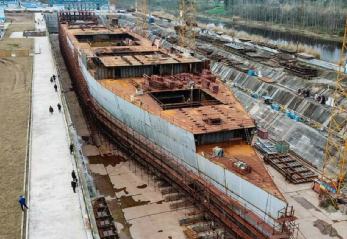 四川復刻版「鐵達尼號」2014年5月開建至今仍未完工。有網民近日發布航拍影片,指這座藏身於四川大英縣江邊船塢內的巨輪只具雛形鏽跡斑斑。(影片截圖)