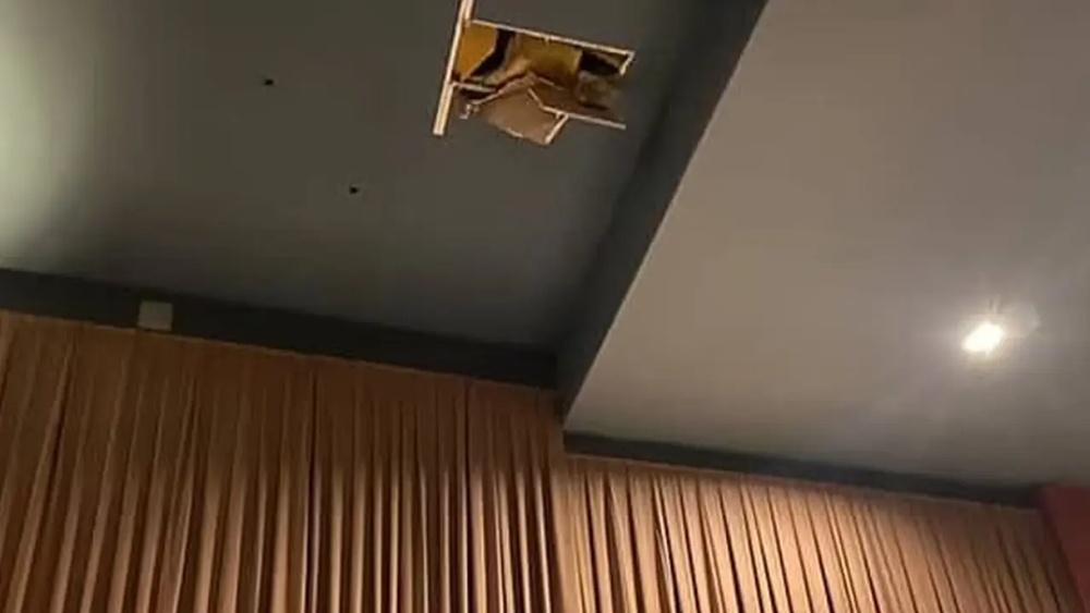 天花板破了一個大洞,碎片散落在走道之間的地板上。(X)