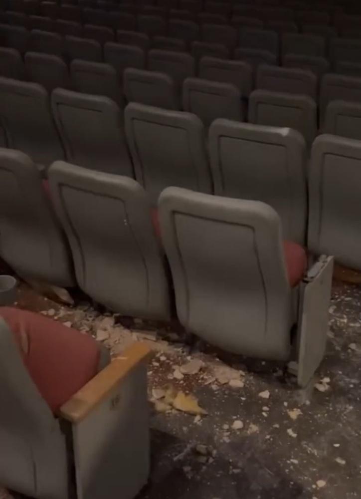 天花板破了一個大洞,碎片散落在走道之間的地板上。(X)