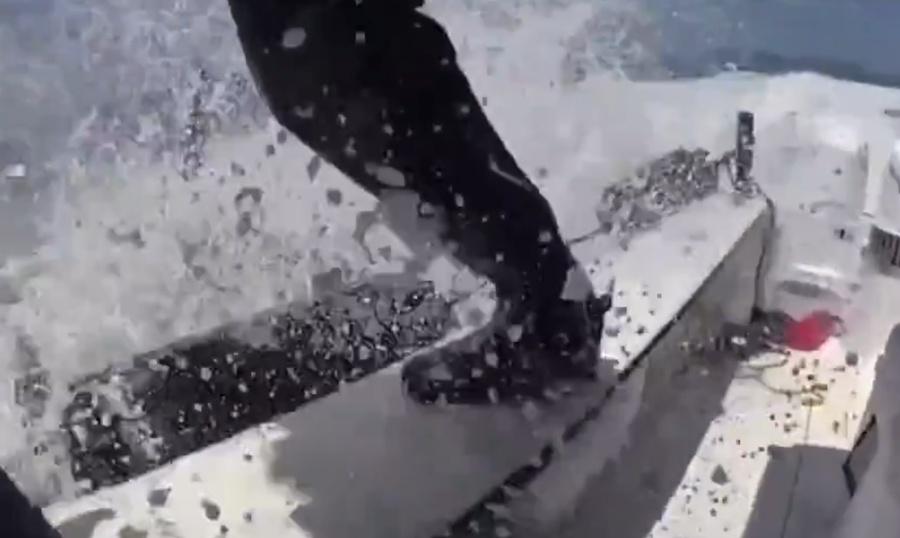 一名海警危站海警船邊,試圖跳上快艇,浪花不停泊打船身和海警雙腿。(X)