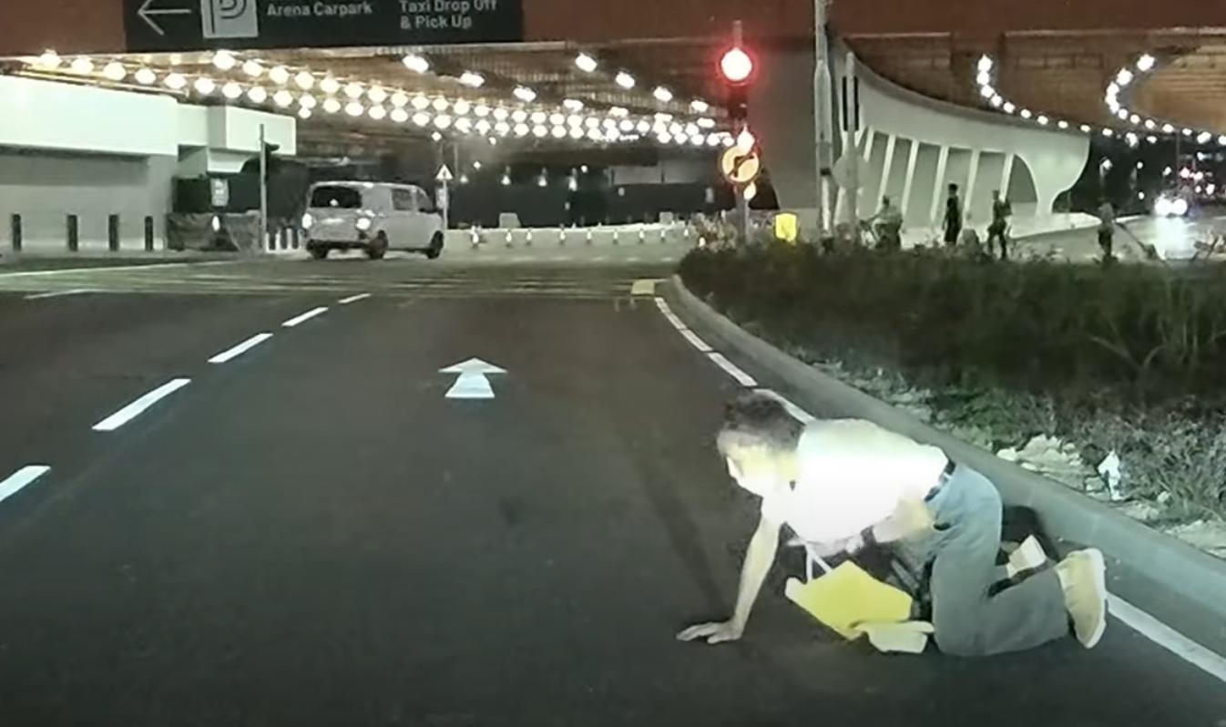 啟德體育園外老翁疑跌傷爬出馬路,好心司機「護駕」扶過路。(YouTube影片截圖)