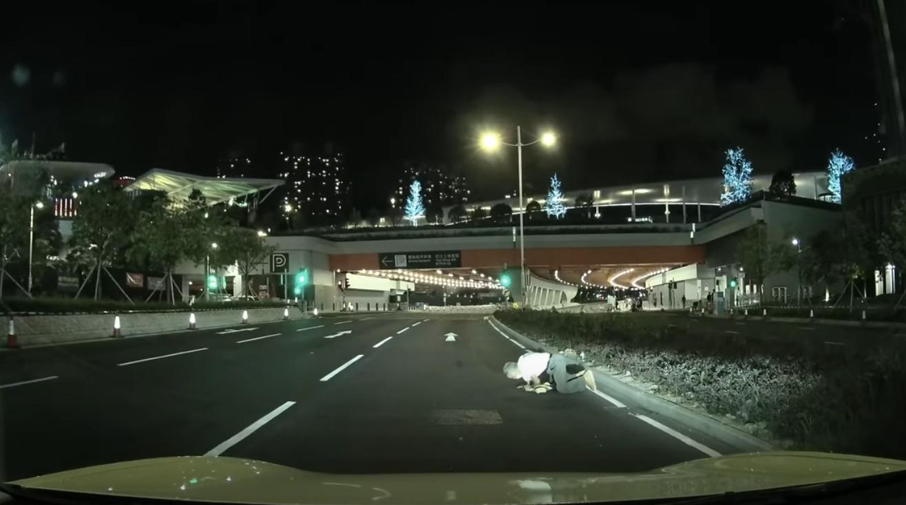 啟德體育園外老翁疑跌傷爬出馬路,好心司機「護駕」扶過路。(YouTube影片截圖)