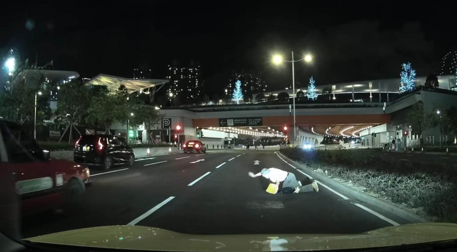 啟德體育園外老翁疑跌傷爬出馬路,好心司機「護駕」扶過路。(YouTube影片截圖)