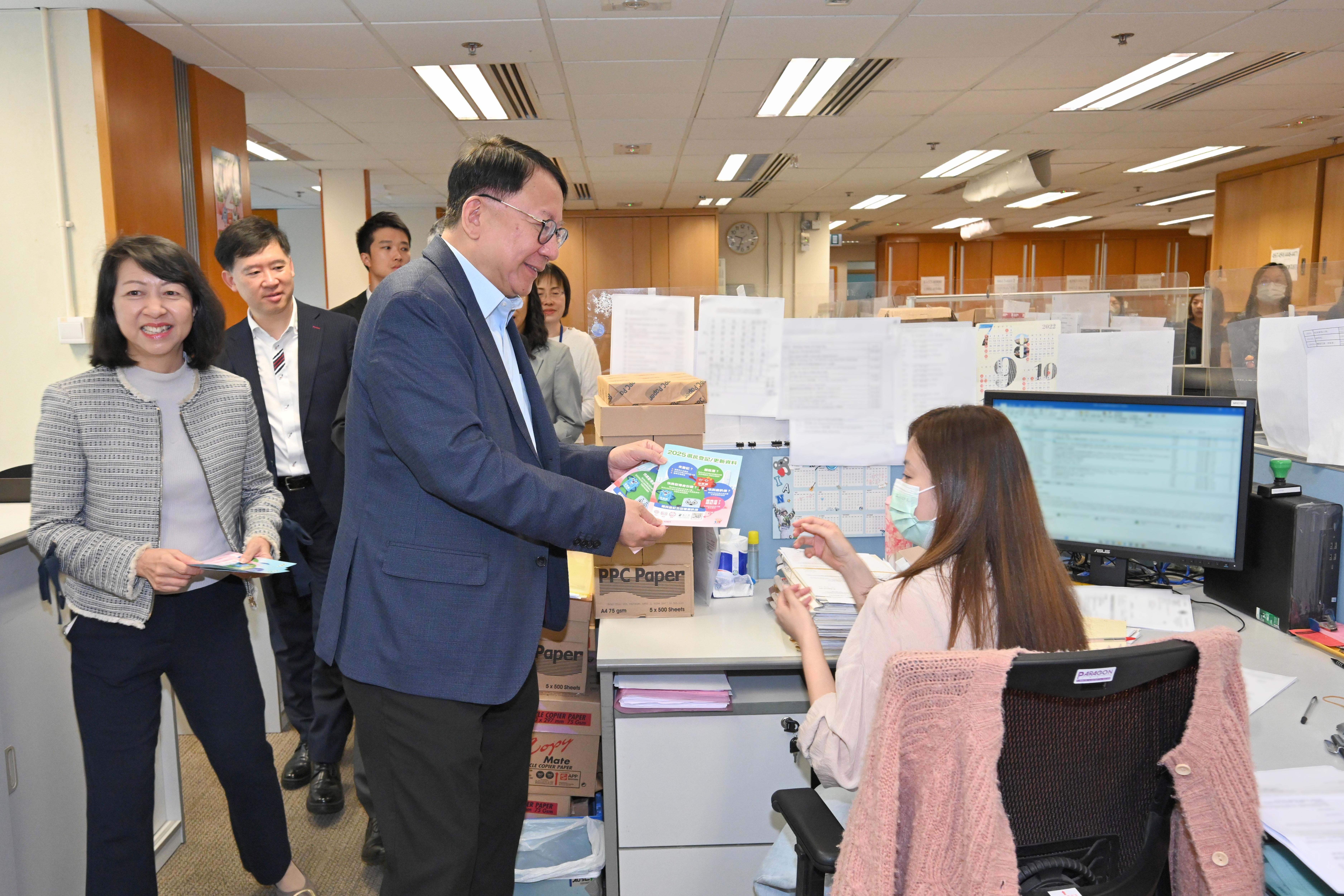 圖示陳國基(右二)在土地註冊處同事的工作間向他們派發宣傳單張。(政府新聞處)