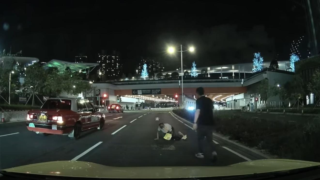 啟德體育園外老翁疑跌傷爬出馬路,好心司機「護駕」扶過路。(YouTube影片截圖)