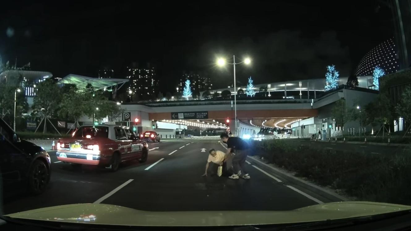 啟德體育園外老翁疑跌傷爬出馬路,好心司機「護駕」扶過路。(YouTube影片截圖)