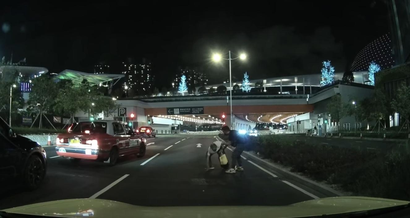 啟德體育園外老翁疑跌傷爬出馬路,好心司機「護駕」扶過路。(YouTube影片截圖)