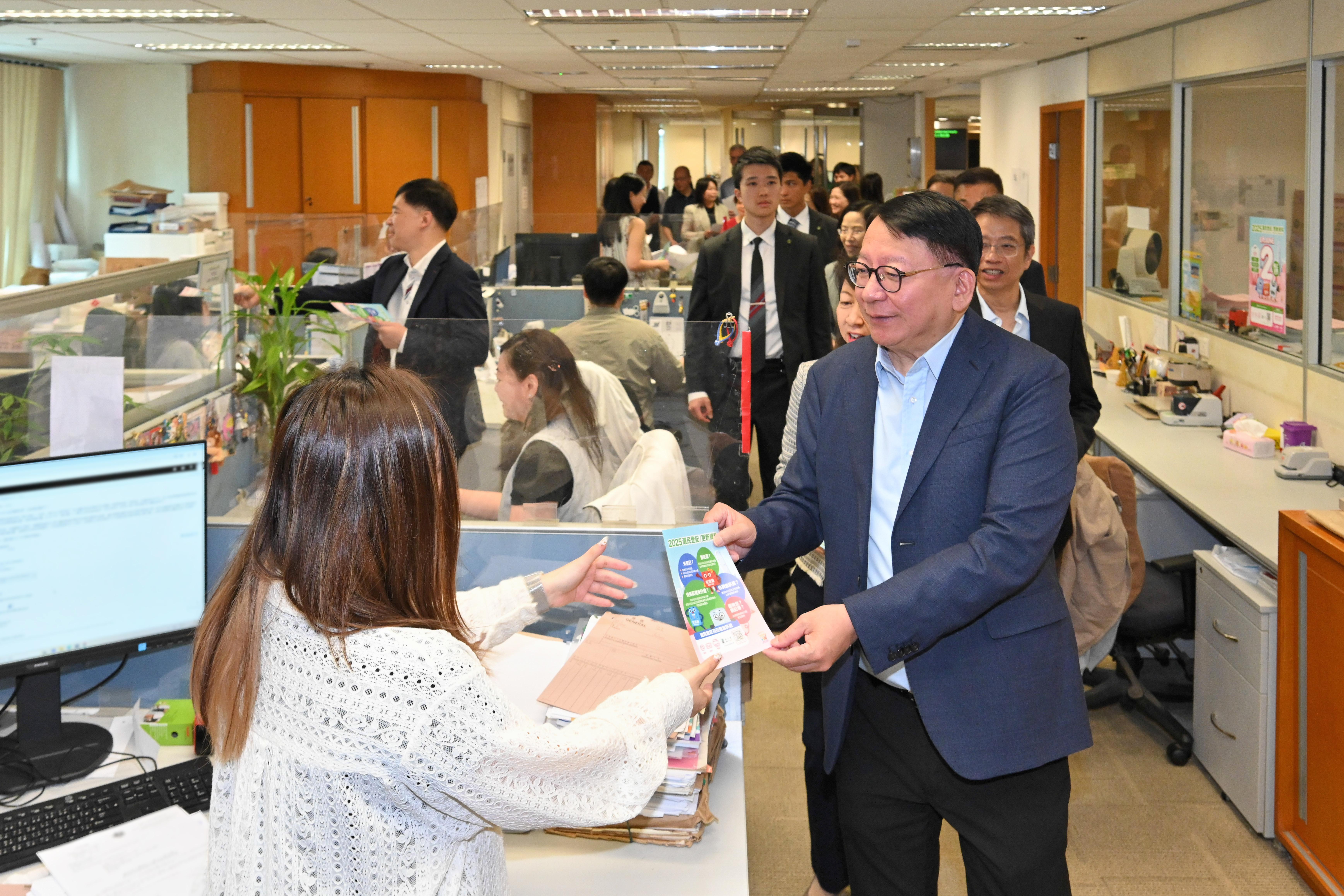 圖示陳國基(右)在土地註冊處同事的工作間向他們派發宣傳單張。(政府新聞處)