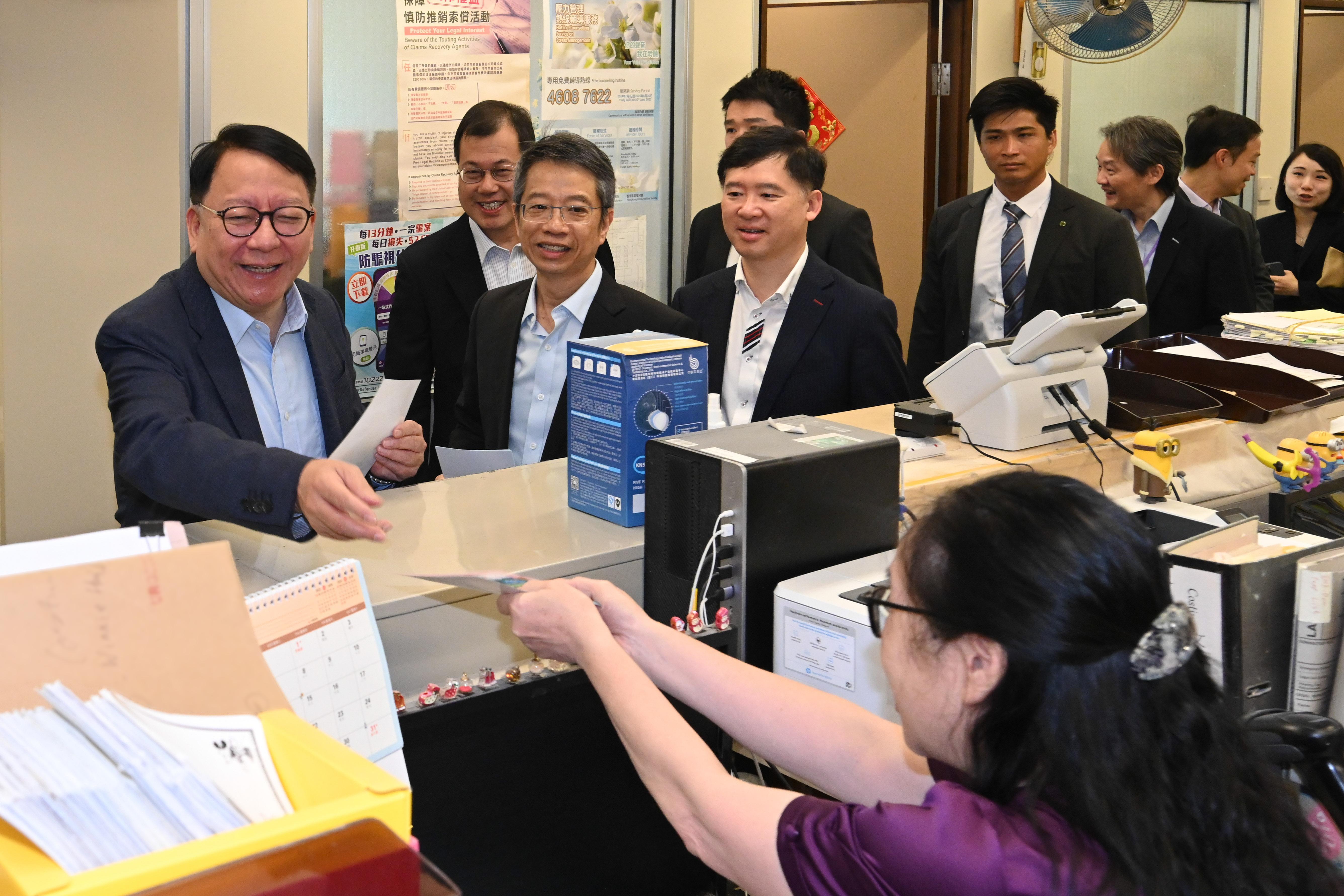 圖示陳國基(左一)在法律援助署同事的工作間向他們派發宣傳單張。(政府新聞處)