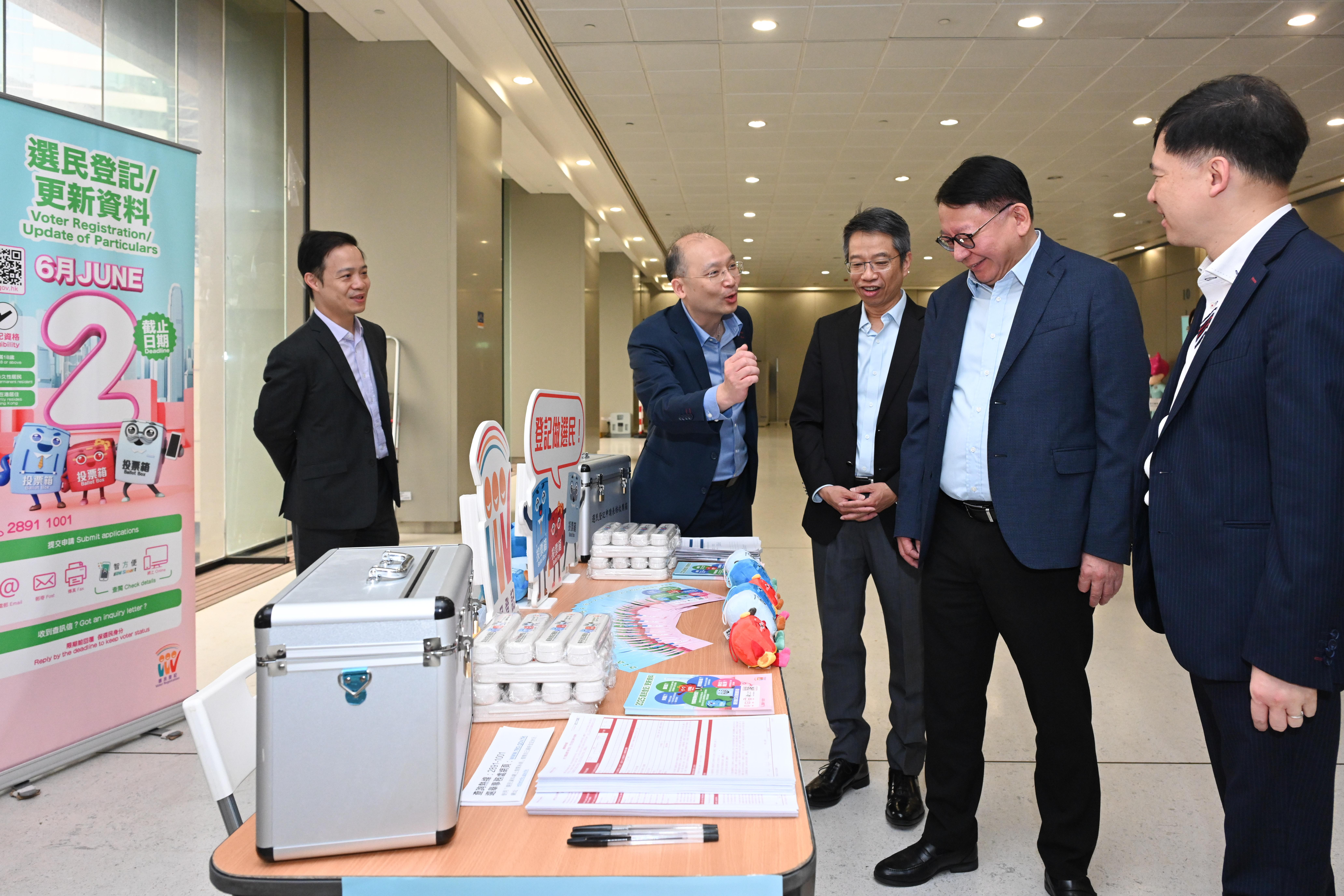 圖示陳國基(右二)、署理政制及內地事務局局長胡健民(右一)和公務員事務局常任秘書長梁卓文(中)參觀由選舉事務處於金鐘政府合署設立的流動選民登記站。(政府新聞處)