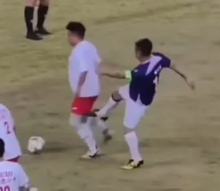 紫藍色波衫嘅10號球員,喺被白衫紅褲嘅對手從後偷波之後,居然出腳踢人。