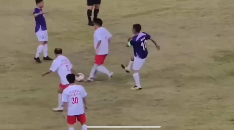 紫藍色波衫嘅10號球員,喺被白衫紅褲嘅對手從後偷波之後,居然出腳踢人。