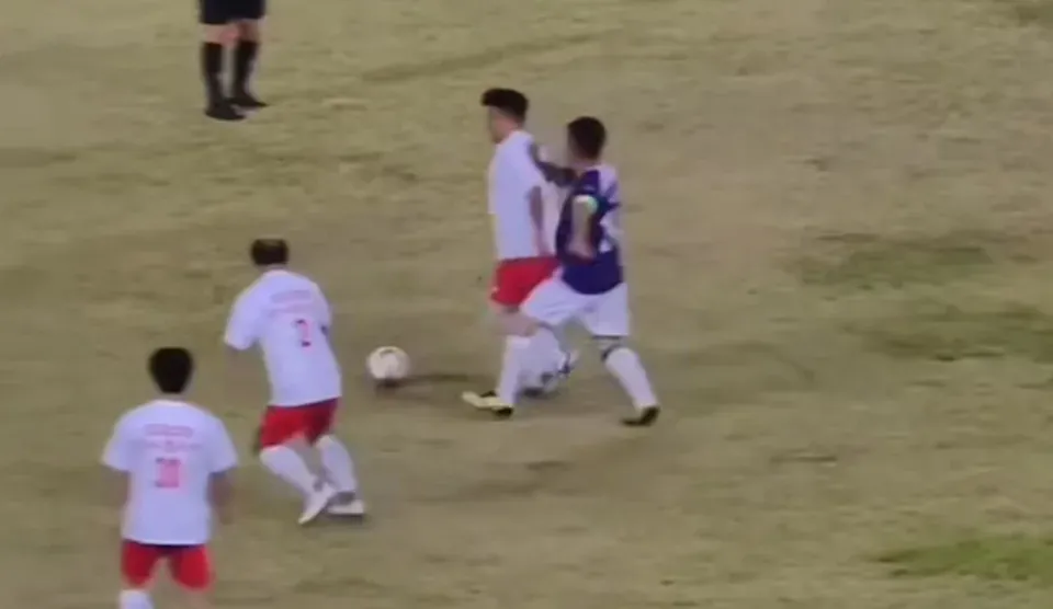 紫藍色波衫嘅10號球員,喺被白衫紅褲嘅對手從後偷波之後,居然出腳踢人。