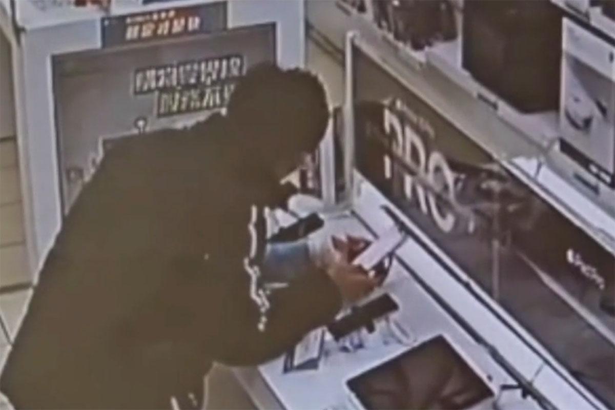 左手正打石膏的竊賊,在電子產品連鎖店「試用」展示的iPhone 16 Plus。(閉路電視影片截圖)