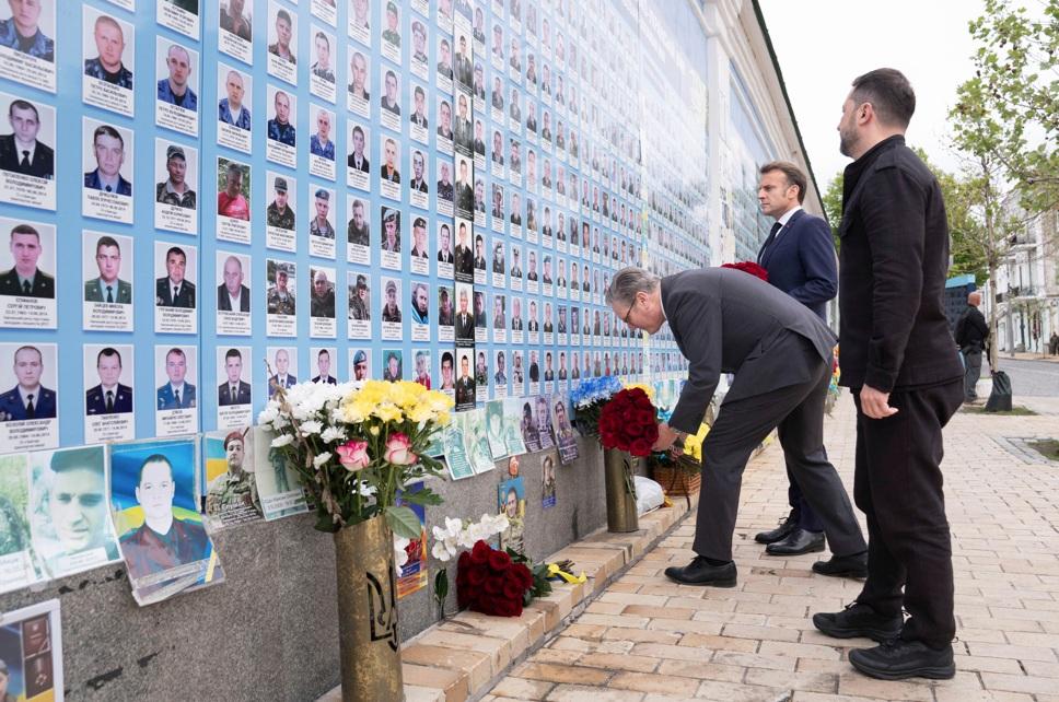 澤連斯基陪同馬克龍及施紀賢到俄烏戰爭紀念牆憑弔,並向陣亡戰士遺像獻花。(美聯社)