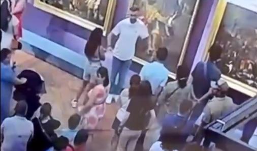 身穿白色上衣的男遊客,在畫作前擺出姿勢,似乎在模仿畫中人物。(X)