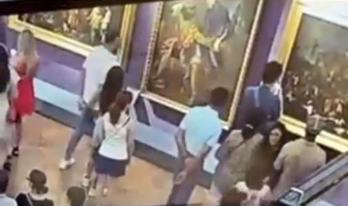 男子察覺有異,立即離開畫作,雙手背負故作沒事一樣去看畫。(X)