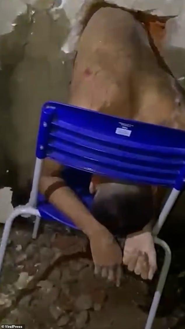 囚犯赤裸上身、背部有刺青,用手撐著一張藍色塑膠椅以承托身體。(YouTube)