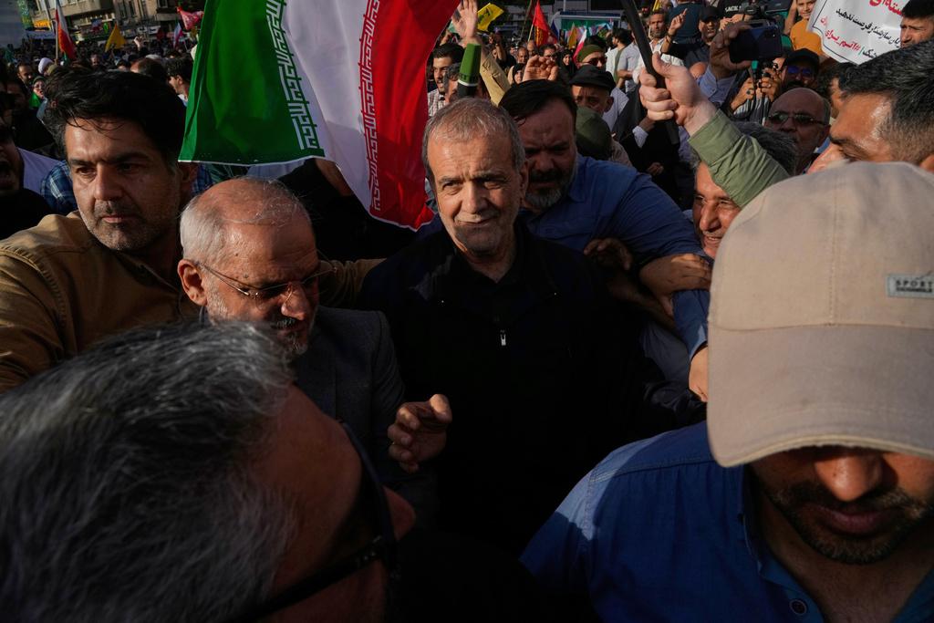 伊朗總統佩澤什基安周日現身德黑蘭反美集會,受到群眾簇擁。(美聯社)