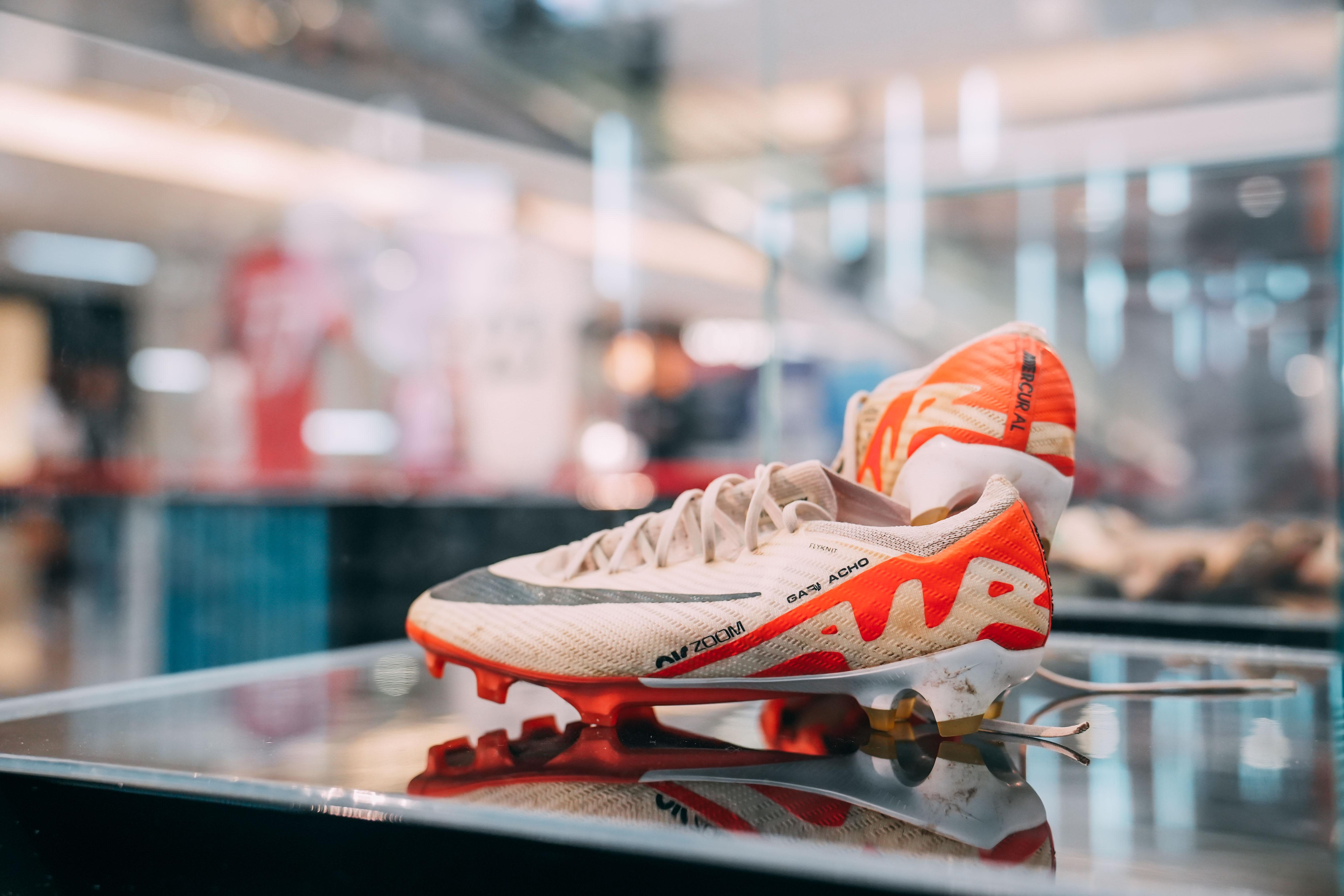 加拿曹穿著過的球鞋,白色鞋身帶有紅黑細節與明顯草地痕跡,鞋面附有球員親筆簽名,具備高度紀念價值。