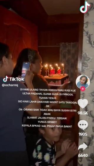 妻子笑著捧蛋糕走進房間為丈夫驚喜慶生,女兒在身後拍片。(互聯網)