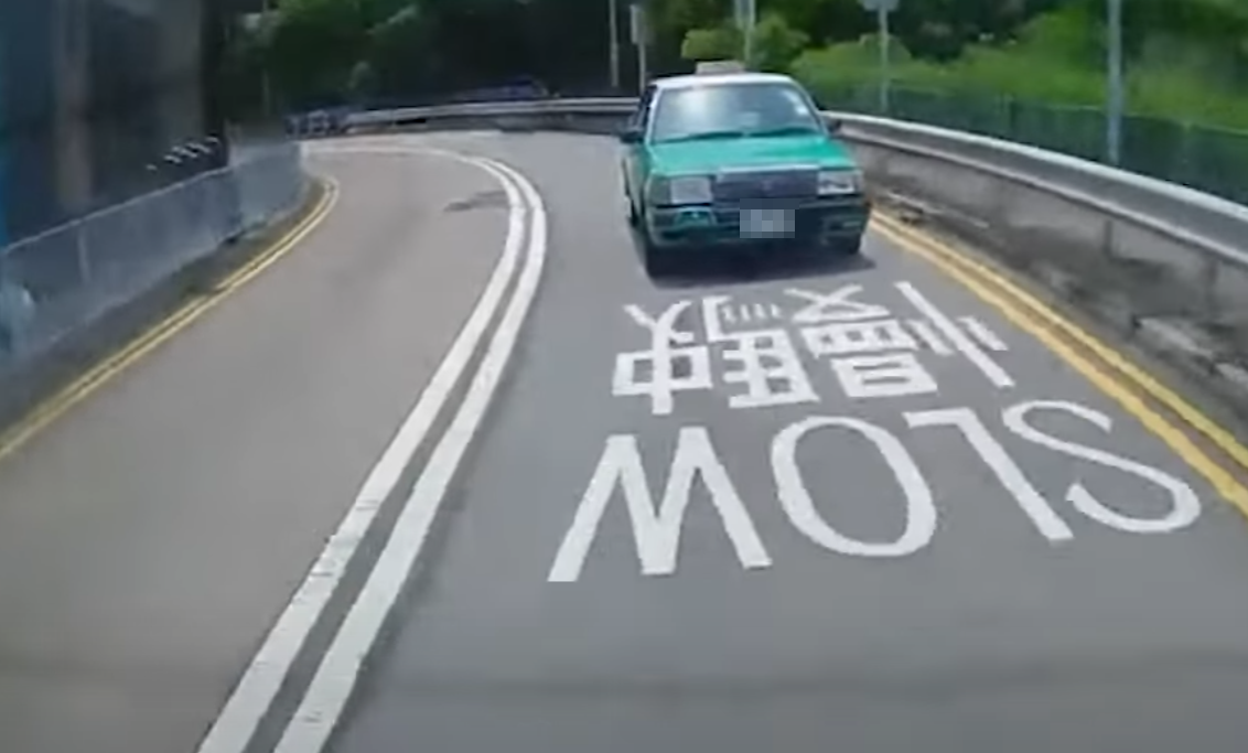 一輛綠色的士在屯門掃管笏管青路斑馬線過路處前,越過雙白線抽頭超越Cam主車輛,再逆線駛過斑馬線,一對母子過路走至一半時及時停下。(影片截圖)