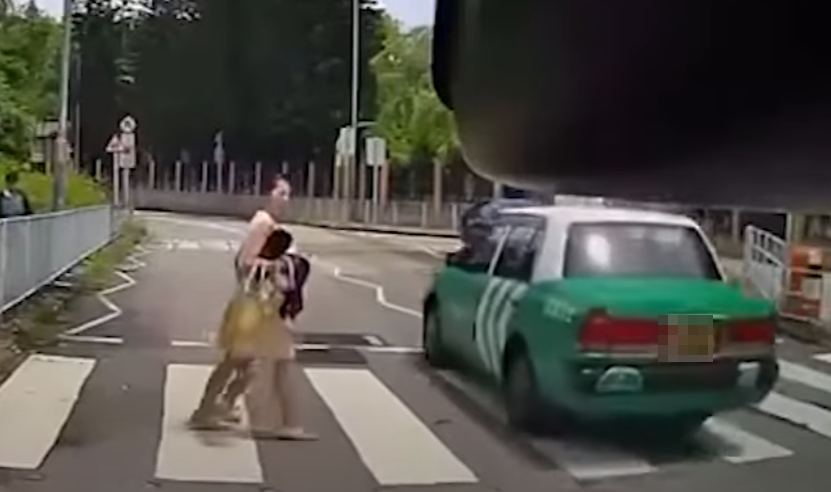 一輛綠色的士在屯門掃管笏管青路斑馬線過路處前,越過雙白線抽頭超越Cam主車輛,再逆線駛過斑馬線,一對母子過路走至一半時及時停下。(影片截圖)