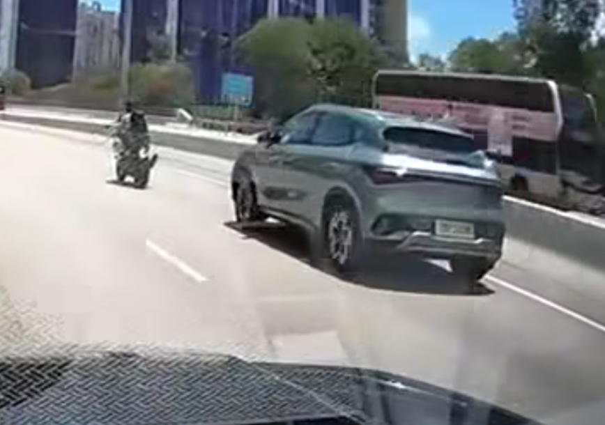屯門公路一輛電單車往九龍方向快線行駛,至珠海學院對開時被一輛銀色私家車從後逼近,更加速強行切入電單車與路中石壆之間的狹窄空位爬頭,導致雙方擦撞險釀意外。(車cam L(香港群組)fb)