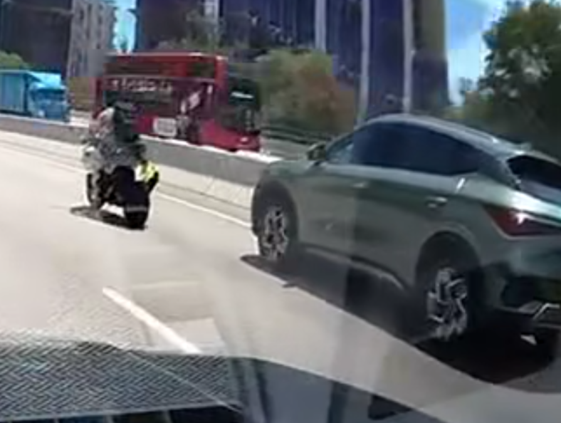 屯門公路一輛電單車往九龍方向快線行駛,至珠海學院對開時被一輛銀色私家車從後逼近,更加速強行切入電單車與路中石壆之間的狹窄空位爬頭,導致雙方擦撞險釀意外。(車cam L(香港群組)fb)
