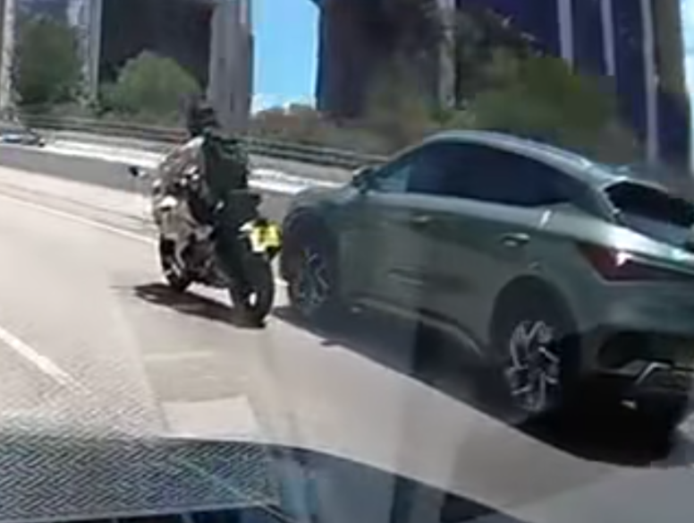 屯門公路一輛電單車往九龍方向快線行駛,至珠海學院對開時被一輛銀色私家車從後逼近,更加速強行切入電單車與路中石壆之間的狹窄空位爬頭,導致雙方擦撞險釀意外。(車cam L(香港群組)fb)