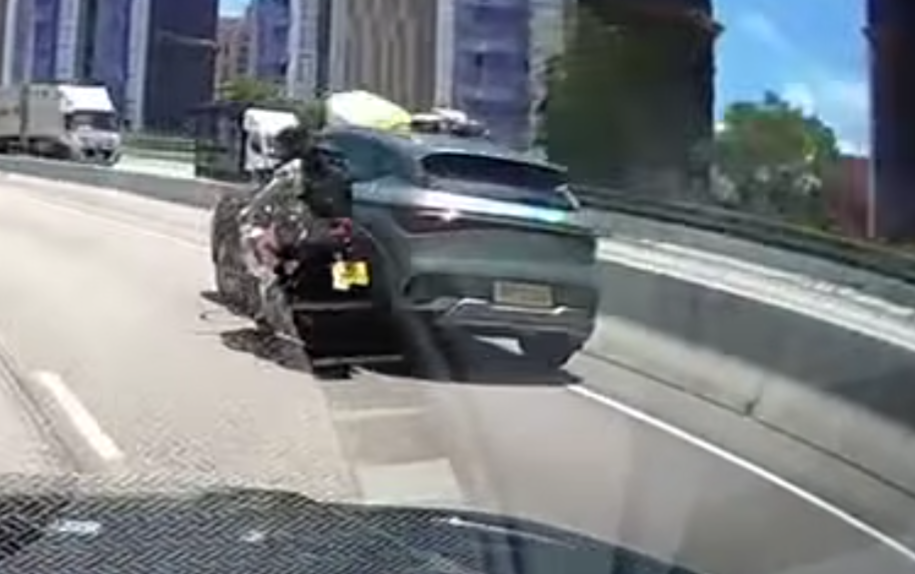 屯門公路一輛電單車往九龍方向快線行駛,至珠海學院對開時被一輛銀色私家車從後逼近,更加速強行切入電單車與路中石壆之間的狹窄空位爬頭,導致雙方擦撞險釀意外。(車cam L(香港群組)fb)