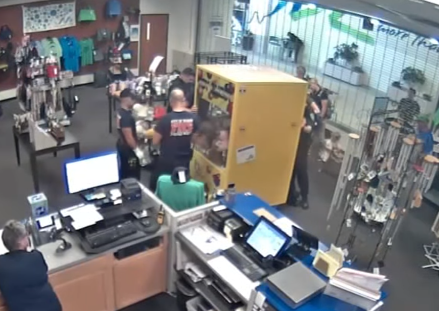 警員在店倫內把夾公仔機的後門打開救出小童。(影片截圖)