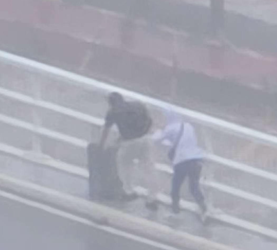 澳門兩名旅客推着行李箱,經嘉樂庇總督大橋由澳門半島行向氹仔。治安警察局接報後,協助兩人返回安全地點,由於兩人違反現場按道路交通規章相關規定設立的禁止行人通行符號,已依法被檢控。(影片截圖)